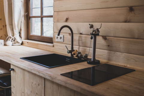 Modern wooden kitchen with black sink and stove in Bird Nest tree house, Belgium, featuring window view.