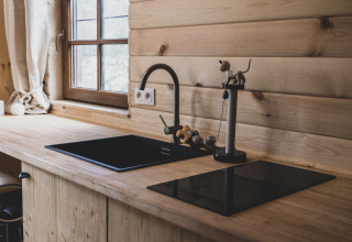 Modern wooden kitchen with black sink and stove in Bird Nest tree house, Belgium, featuring window view.