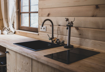 Cucina moderna in legno con lavello e piano nero nella casa sull'albero Bird Nest in Belgio, vicino a finestra.