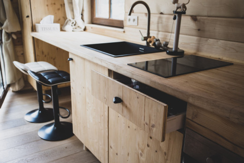 Modern treehouse kitchen at Bird Nest in Belgium, featuring black sink, cooktop, and wood cabinets.