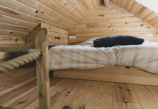 Cozy sleeping area with low bed and wood paneling in the «Bird Nest» tree house, Belgium, interior view.