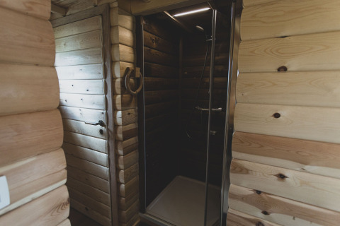 Modern glass shower cabin in wooden interior, photographed at the Bird Nest tree house in Belgium.