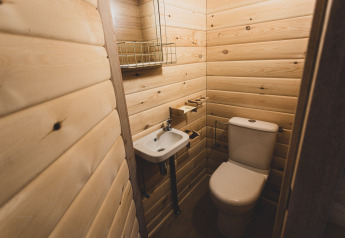 Piccolo bagno moderno con pannelli in legno chiaro, WC e lavabo in una casa sull'albero in Belgio.