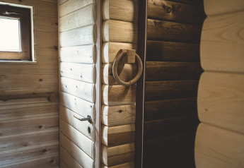 Innenaufnahme eines Baumhauses in Belgien mit rustikalen Holzwänden, Fenstern und Türdetails.