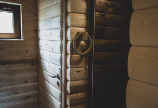 Interior view of the Bird Nest tree house in Belgium, showing rustic wooden walls, door and window.