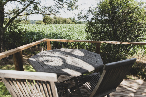 Tavolo e sedie di legno su terrazza con vista sui campi dal treehouse Bird Nest in Belgio.