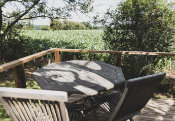 Tavolo e sedie di legno su terrazza con vista sui campi dal treehouse Bird Nest in Belgio.