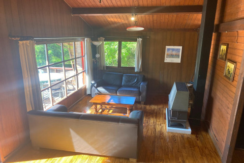 Houten woonkamer in chalet 'La Bressine' in België met banken, groot raam en verwarming.