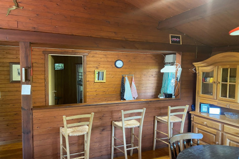 Gezellig houten interieur van chalet La Bressine in België met barkrukken, keuken en kast.