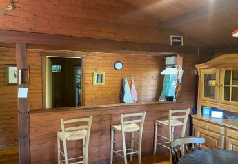 Knus houten interieur van chalet La Bressine in België met barkrukken, keuken en vitrinekast.