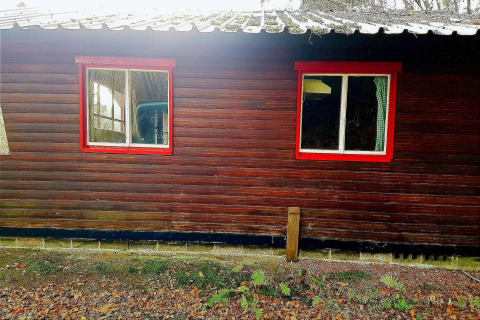 Een chalet genaamd La Bressine in België met donkere houten panelen en rode raamkozijnen.