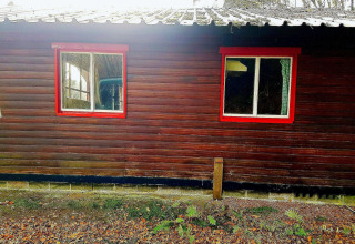 Een chalet genaamd La Bressine in België met donkere houten panelen en rode raamkozijnen.