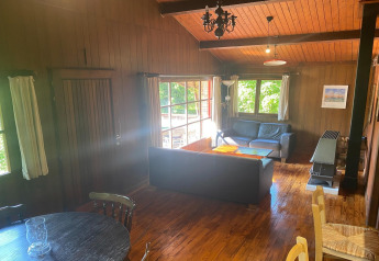 Gezellige leefruimte in chalet La Bressine in België, houtbekleed, met grote ramen en twee zitbanken.