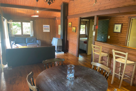 Houten woonkamer in chalet 'La Bressine', België, met eethoek, zithoek en open keukenbar.