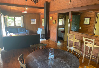 Woonruimte in chalet 'La Bressine' in België met houten interieur, eettafel, zithoek en ontbijthoek.