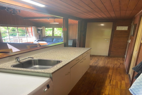 Keuken en woonkamer van chalet La Bressine in België, met houten wanden en grote ramen voor licht.