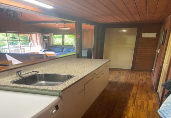 Keuken en leefruimte van chalet La Bressine in België, met veel houtwerk en royale raampartijen.