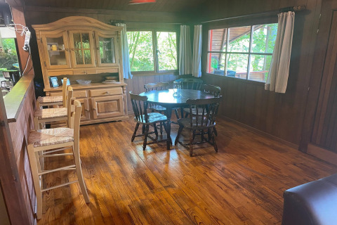 Houten eetkamer in chalet La Bressine in België met ronde tafel, stoelen en grote ramen.