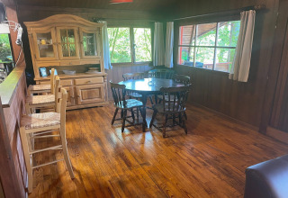 Houten eetkamer in chalet La Bressine in België met ronde tafel, stoelen en grote ramen.