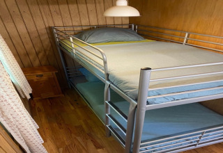 Kleine kamer in chalet La Bressine in België met metalen stapelbed en houten wandbekleding.
