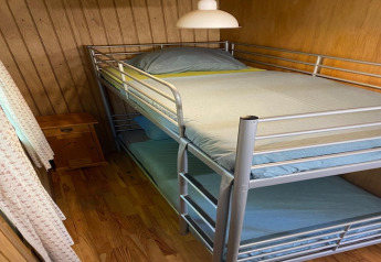 Kleine kamer in chalet La Bressine in België met metalen stapelbed en houten wandbekleding.
