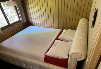 Slaapkamer in chalet La Bressine in België met dubbel bed tegen houten lambrisering.