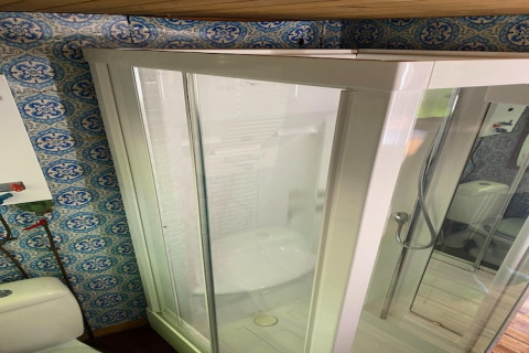 Douchecabine met glazen deur en sierlijke tegels in de badkamer van chalet La Bressine in België.