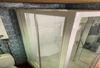 Douchecabine met glazen deur en sierlijke tegels in de badkamer van chalet La Bressine in België.