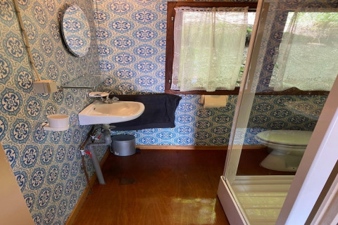 Badkamer in chalet La Bressine in België met patroonbehang, wasbak, douche en raam.
