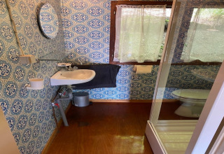 Badkamer in chalet La Bressine in België met patroonbehang, wasbak, douche en raam.