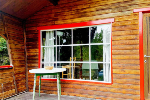 Houten terras met groene tafel en roodomrand raam bij chalet 'La Bressine' in België.