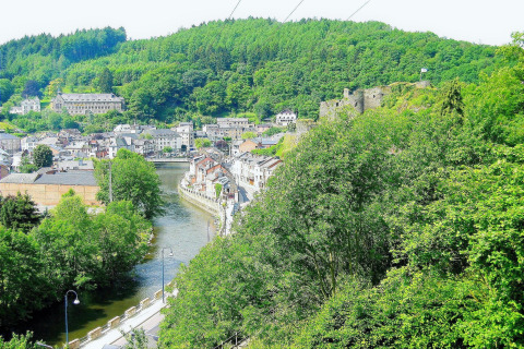Uitzicht vanaf chalet 'La Bressine' in België op groene heuvels, rivier, stad en een oud kasteel.