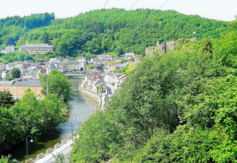 Zicht vanuit chalet 'La Bressine' in België, met groene heuvels, rivier en een oud kasteel in de verte.