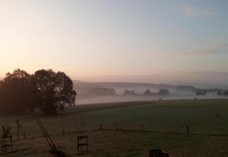 Landelijk uitzicht bij zonsopkomst met mist, velden en bomen, gezien vanaf chalet La Bressine in België.