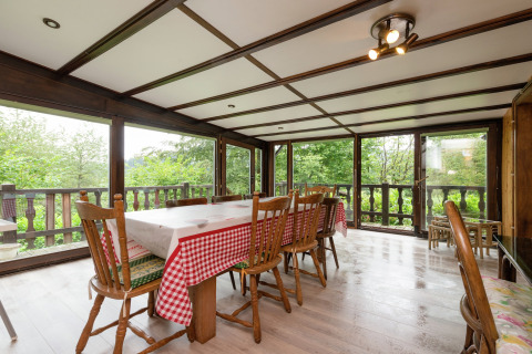 Eetkamer met houten stoelen, grote ramen en uitzicht op het groen in lodge Le Chession in België.