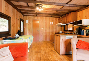 Gemütlicher Wohnbereich in der Lodge Le Chession, Belgien, mit Holzwänden, Küche und Essbereich.