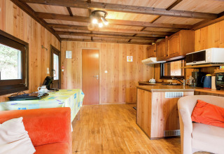Knus houten interieur van Le Chession lodge in België met keuken, eettafel en comfortabele fauteuils.