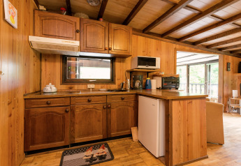 Rustikale Holzküche mit Kühlschrank, Mikrowelle, Kaffeemaschine und Fenster in einer belgischen Lodge.