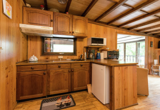 Rustieke keuken met houten kasten, kleine apparaten en raam in een lodge in België.