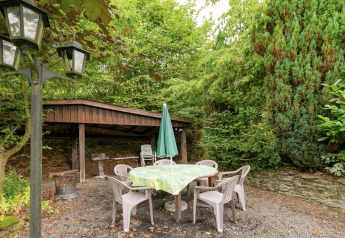Gemütlicher Außenbereich bei 'Le Chession' in Belgien mit Gartentisch, Stühlen und viel Grün.
