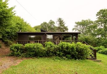 Holzlodge im Grünen bei Le Chession in Belgien, von vorne fotografiert mit Veranda und Stufen.