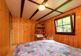 Holzverkleidetes Schlafzimmer mit Bett, Regal und Fenster in der Lodge Le Chession in Belgien.
