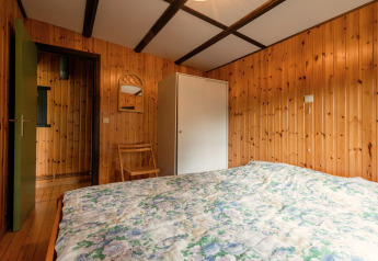 Schlafzimmer in einer holzverkleideten Lodge mit Doppelbett und Schrank im Le Chession, Belgien.