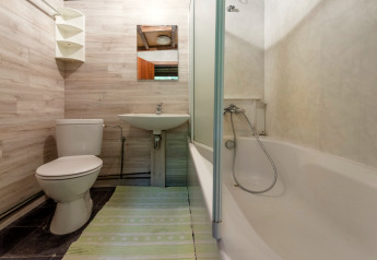 Badezimmer mit WC, Waschbecken, Spiegel, Badewanne und grünem Teppich in der Lodge Le Chession, Belgien.