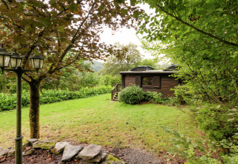 Foto einer gemütlichen Lodge namens Le Chession, umgeben von Natur und Bäumen in Belgien.