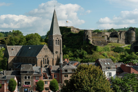Uitzicht vanaf lodge Le Chession in België, met een oude kerk en kasteel tussen groen in het landschap.