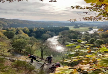 Blick auf das Tal und den Fluss nahe der Lodge Le Chession in Belgien, mit Menschen auf einer Leiter.