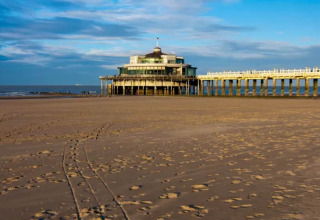 Playa con huellas y un muelle con edificio circular, foto tomada en el Resort Beachside 5 en Bélgica.