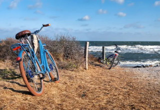 Dos bicicletas aparcadas junto al mar en el Resort «Beachside 5» en Bélgica, el cielo está azul.