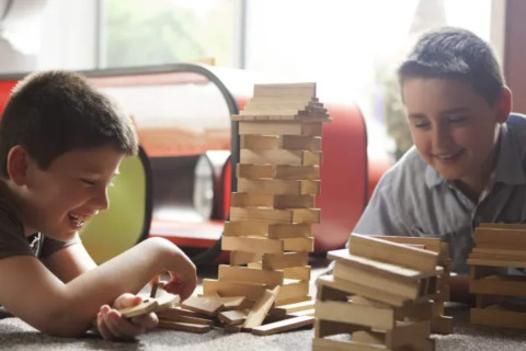 Dos niños juegan felices con bloques de madera en una tienda tipo safari del Resort «Beachside 5» en Bélgica.